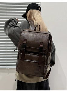 Detalle de mochila vintage de cuero marrón oscuro con doble hebilla mostrada por un modelo