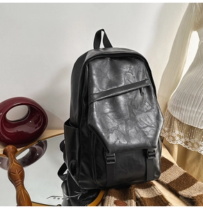 Detail of vintage black leather backpack with utility buckles and textured finish