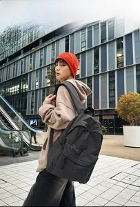 Outdoor model display of a casual grey checkered backpack with a front zipper pocket
