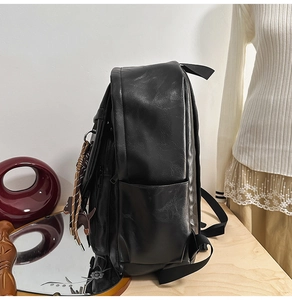 Side view of black PU leather backpack showing texture and cute cat charm detail