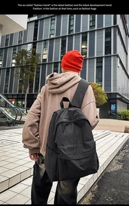 Outdoor view of a checked nylon backpack with wide straps on a person's back