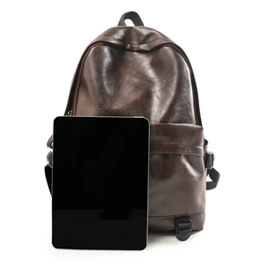 Detail of dark brown leather backpack showing retro PU texture and front zipper pocket