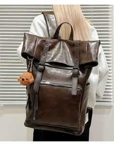 Detail view of large brown vintage leather backpack with stylish buckle straps and bear charm