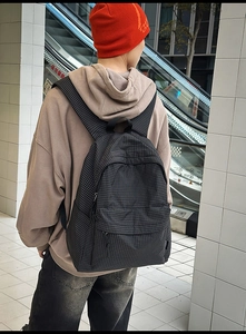 Side view of a black and white checkered nylon backpack with a front zipper pocket