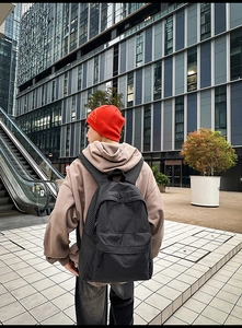 Outdoor shot of a woman wearing a black checkered nylon backpack in a modern city setting
