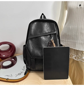 Detail of black PU leather backpack showing texture, flap closure, and chocolate charm