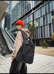 Detail of grey and black checkered nylon backpack showing side pocket and large main compartment