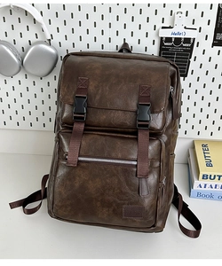 Détail d'un sac à dos vintage marron avec doubles fermoirs à boucles et poche frontale