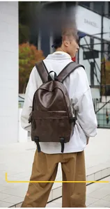 Rear view of a dark brown PU leather backpack on a model in an urban outdoor setting