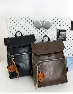 Detailed close-up of retro leather backpack featuring a cute bear plush pendant charm