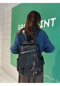 Detail of black leather backpack featuring functional pockets and a dachshund dog pendant