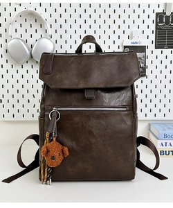 Detail of dark brown leather backpack with retro texture and cute plush puppy keychain