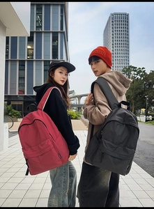 Detail of red and black checkered nylon backpacks shown on models in urban setting
