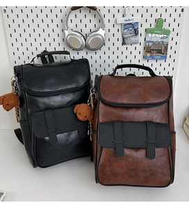 Detail view of stylish PU leather backpacks in black and brown with plush bear charms