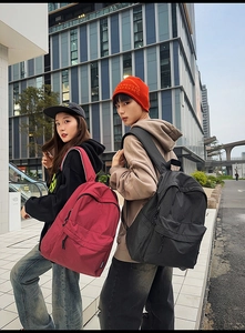 Detail view of red and black plaid nylon backpacks with multiple pockets for daily use