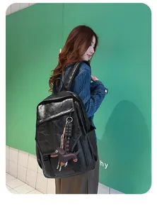 Close-up of black PU leather backpack texture featuring a cute dachshund dog pendant