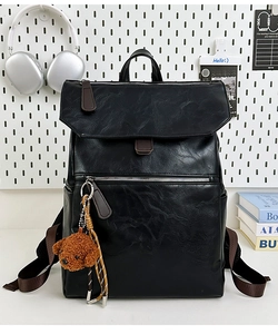 Detail of black PU leather backpack with brown leather strap and teddy bear charm