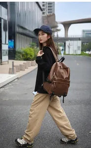 Side view of dark brown pebbled leather backpack showing multiple zipper compartments
