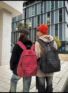 Detail showing Burgundy and Charcoal Black nylon grid backpacks on models in city street