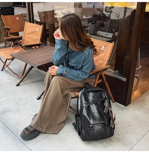 Detail of vintage black leather backpack featuring foldover buckle and side pocket detail