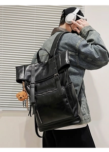 Detail view of black PU leather backpack with vintage metal buckles and a cute bear charm