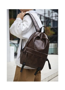 Close-up of brown vintage PU leather backpack with front pocket in outdoor setting