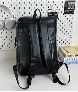 Detalle de la espalda de la mochila de cuero negro con correas y un bolsillo con cremallera