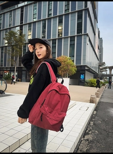 Detailed side view of the red plaid nylon backpack on a model in an urban city setting