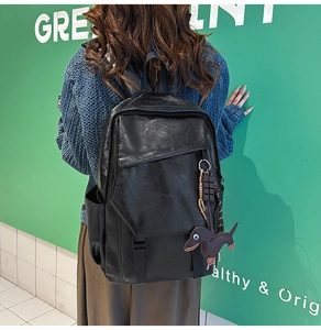 Outdoor shot of a black matte PU leather backpack featuring a cute dachshund dog charm