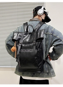 Detail of black PU leather backpack featuring flap buckle closure and yellow plush charm