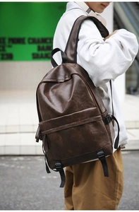 Detail of vintage brown leather backpack with front pocket and adjustable straps on a model