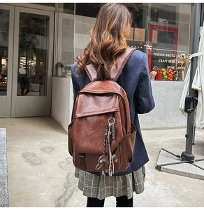 Outdoor lifestyle shot of a brown vintage leather backpack with elephant charm detail