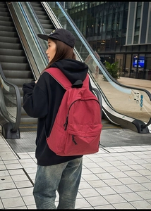 Outdoor view of a student wearing a red and black plaid backpack with nylon straps