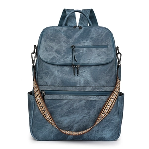 Detail of blue denim backpack showing multi-zipper pockets and ethnic woven strap