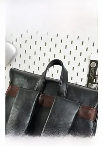 Detail view of reinforced leather handle and nylon straps on a black commuter backpack