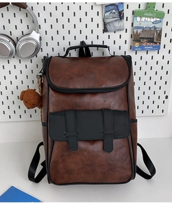 Detail view of vintage brown PU leather backpack with buckle pocket and plush bear charm