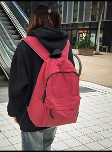 Outdoor shot showing back view of red checkered nylon backpack on model in urban setting