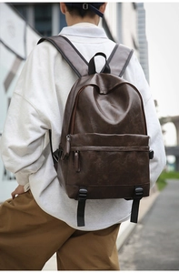 Outdoor street view of a casual dark brown PU leather backpack with minimalist design