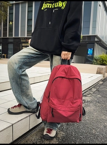 Detail of red checkered nylon backpack with durable handle and reinforced stitching