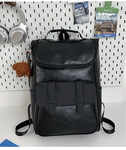 Detail of black PU leather backpack featuring lychee texture and a plush bear pendant