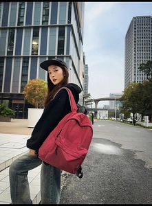 Close-up of red checkered nylon backpack featuring FENRUI logo on a city background