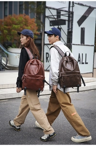 Close-up of vintage brown and coffee leather backpacks on models in an urban setting
