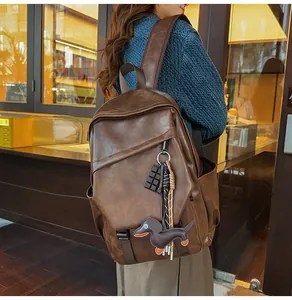 Close-up of brown vintage leather backpack featuring cute chocolate and dachshund charms