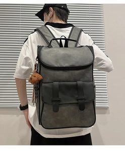 Detailed view of grey PU leather backpack featuring flap cover and brown teddy bear charm