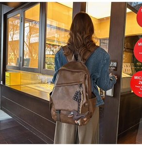 Detail view of dark coffee vintage leather backpack with cute puppy and chocolate charms