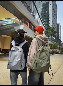 Urban lifestyle shot of couple wearing gray and olive plaid canvas backpacks outdoors
