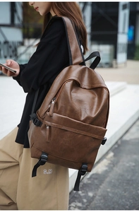 Side view of dark brown PU leather backpack with adjustable side buckles in urban setting