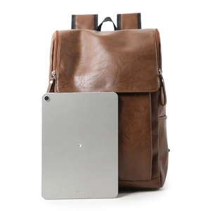 Brown leather backpack with flip-top cover and tablet for size reference on white background