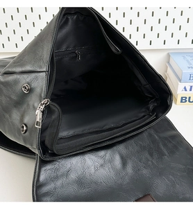 Detailed interior of the black PU leather backpack showing main compartment and zipper pocket