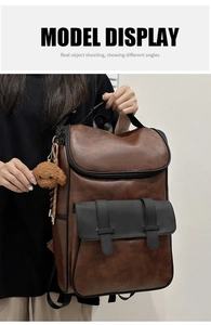 Detail view of large brown PU leather backpack with black buckle pocket and teddy bear charm